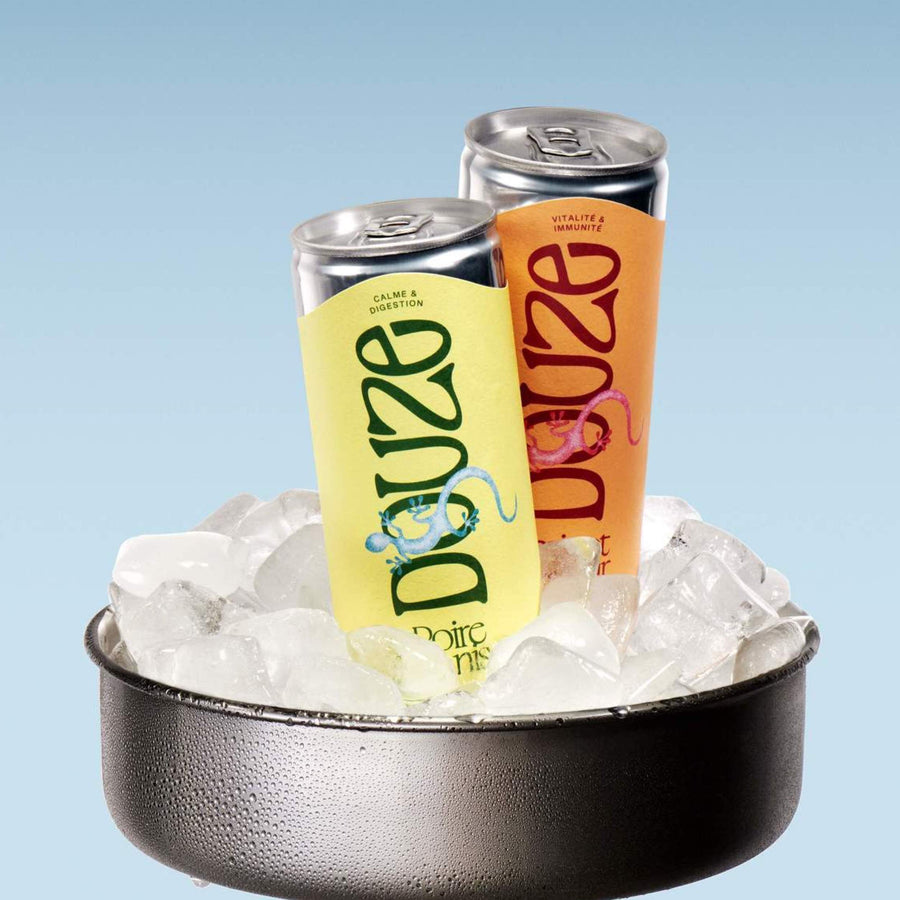 Two Douze beverage cans in bucket of ice or cooler, with blue background. Both drinks are referred to as Douze Duo.