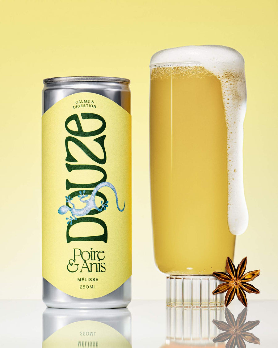 Douze Pear & Anise drink can beside a full, frothy glass filled with golden beverage. One star anise sits against glass. 